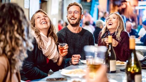 Three friends sat around a table, drinking and laughing.