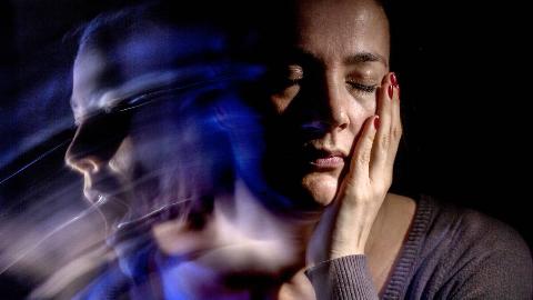 A woman looking pained, a ghostly version of her face looking the other way and crying out.