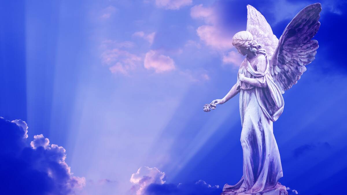 An angel statue reaching down toward light beams breaking through clouds against a vivid blue sky.