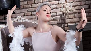 A woman doing a dramatic pose with a white boa across her arms.