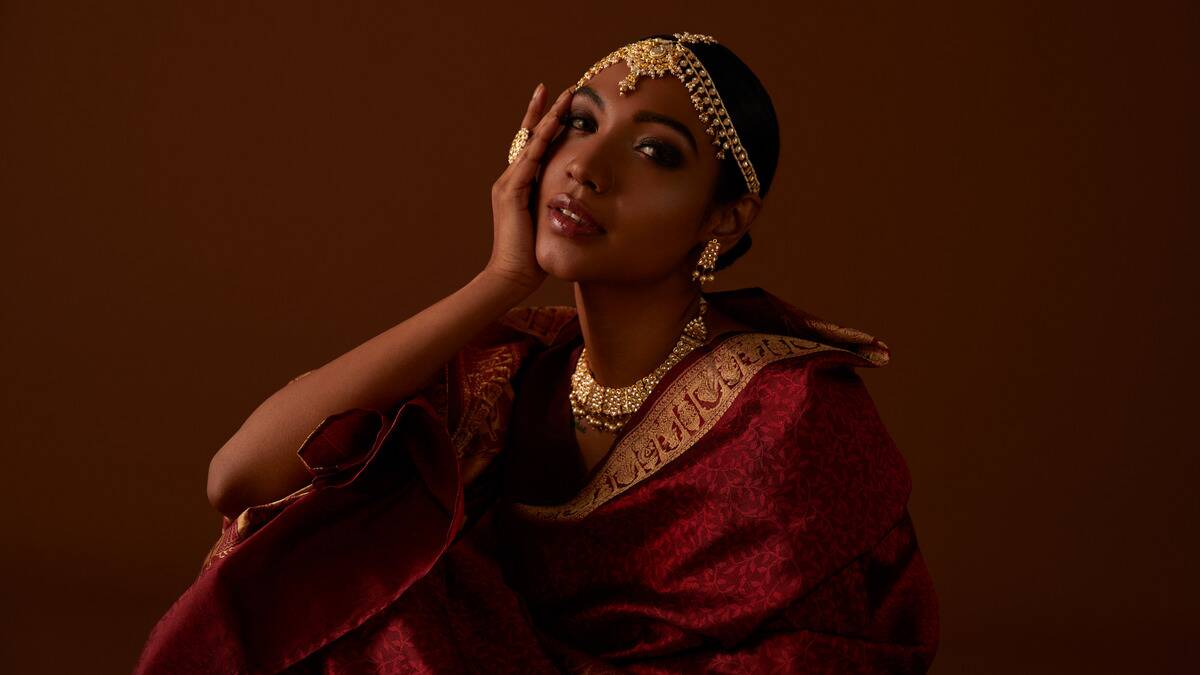 A woman in traditional red and gold Indian clothing and jewelry.