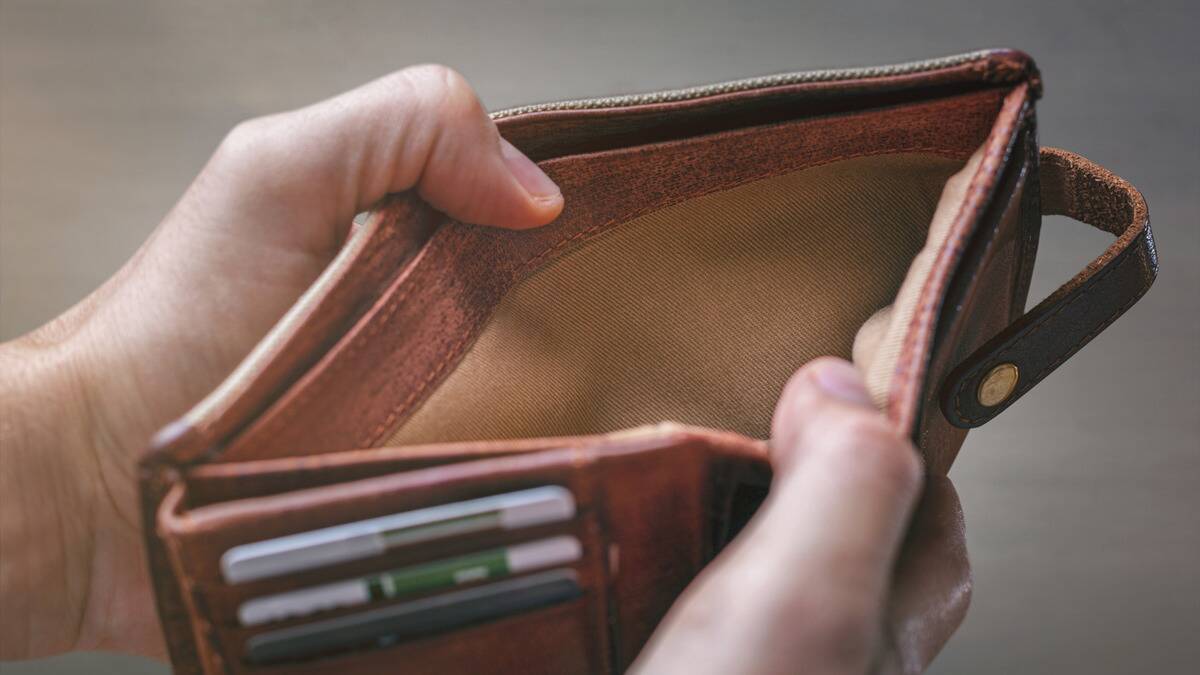 A close shot of a pair of hands holding open a wallet with no cash inside.