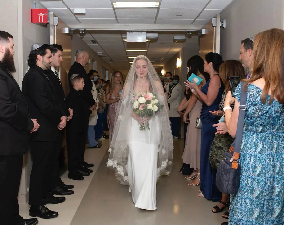 Elisabeth walking down the hospital hallway in her gown, the hall lined with guests, doctors, and wedding party members.