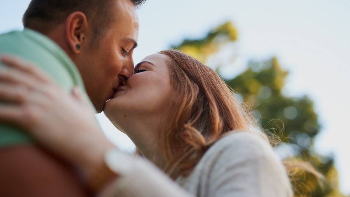 A close, low shot of a couple kissing outdoors.