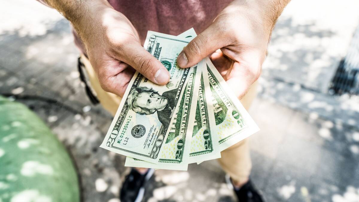 An above angled-shot of someone holding four fanned out $20 bills in their hands.