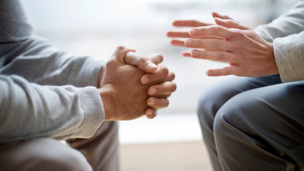 A close shot of two peoples hands as they talk, one person with their hands clasped together and the other gesturing as they speak, presumably.