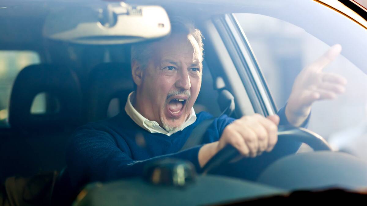 A man yelling angrily in his car gesturing at another driver, presumably.