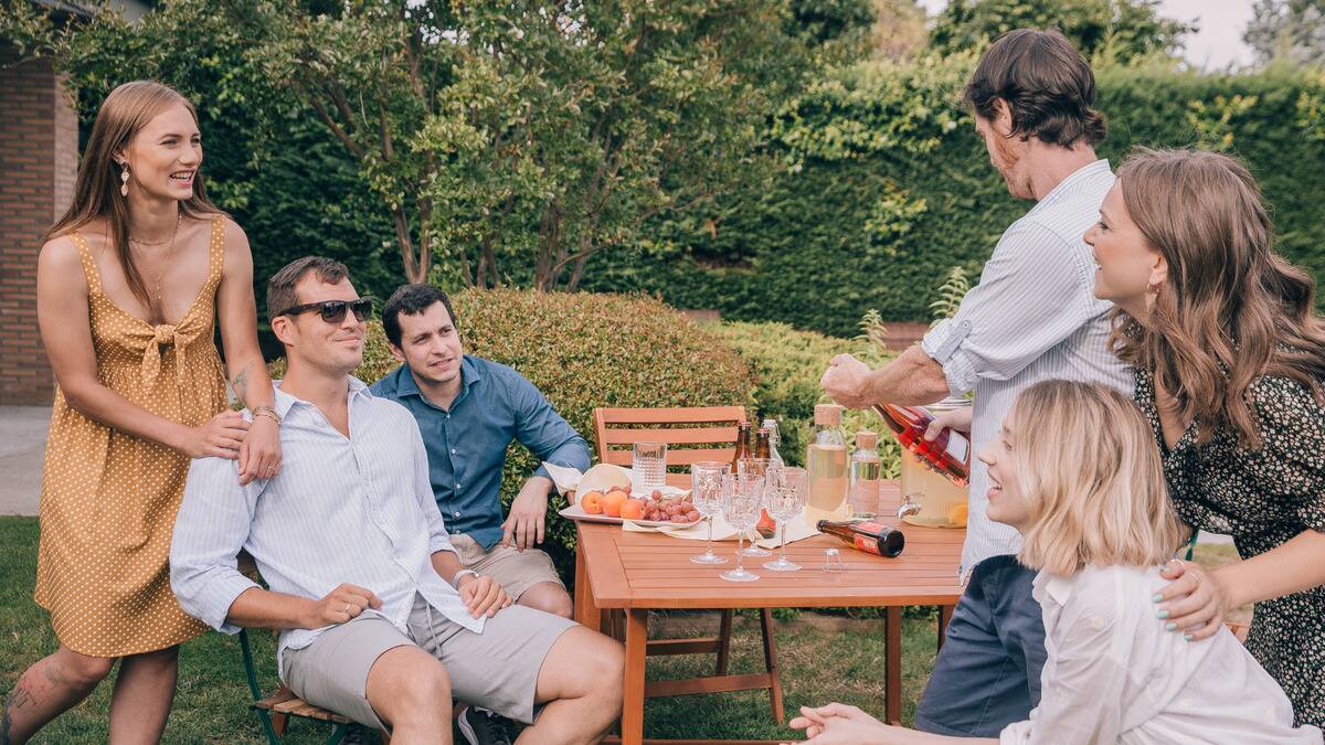 A group of friends around a table for an outdoor dinner party.