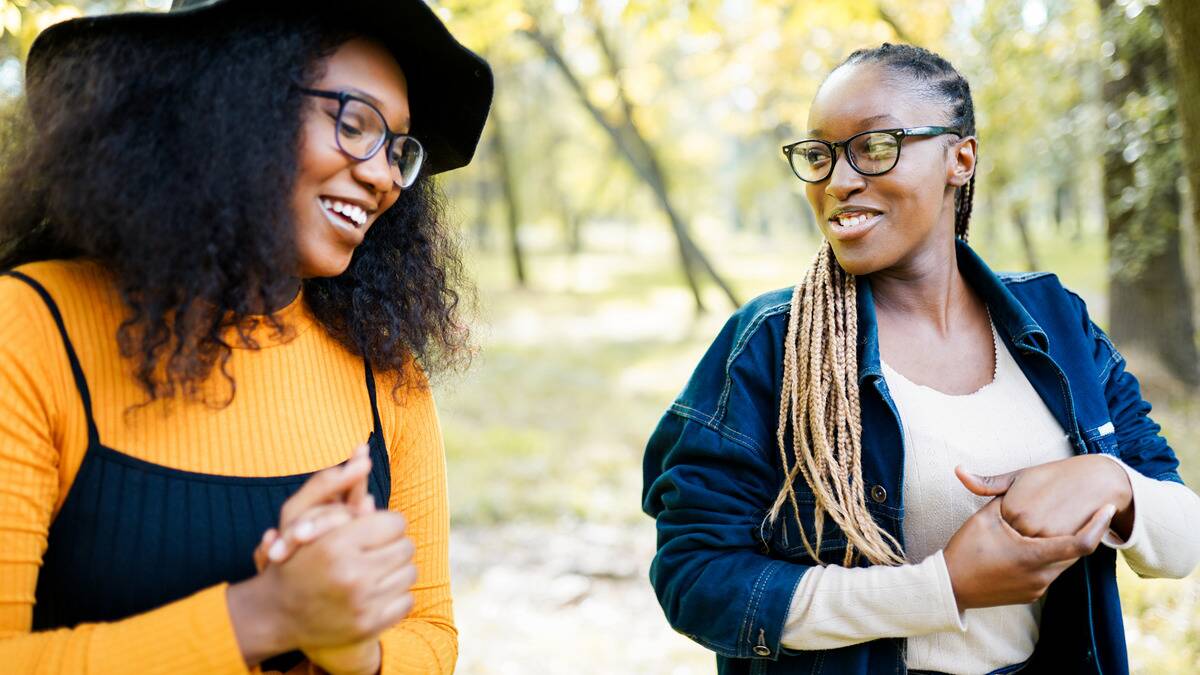 Two friends walking together outside, both smiling as they talk.