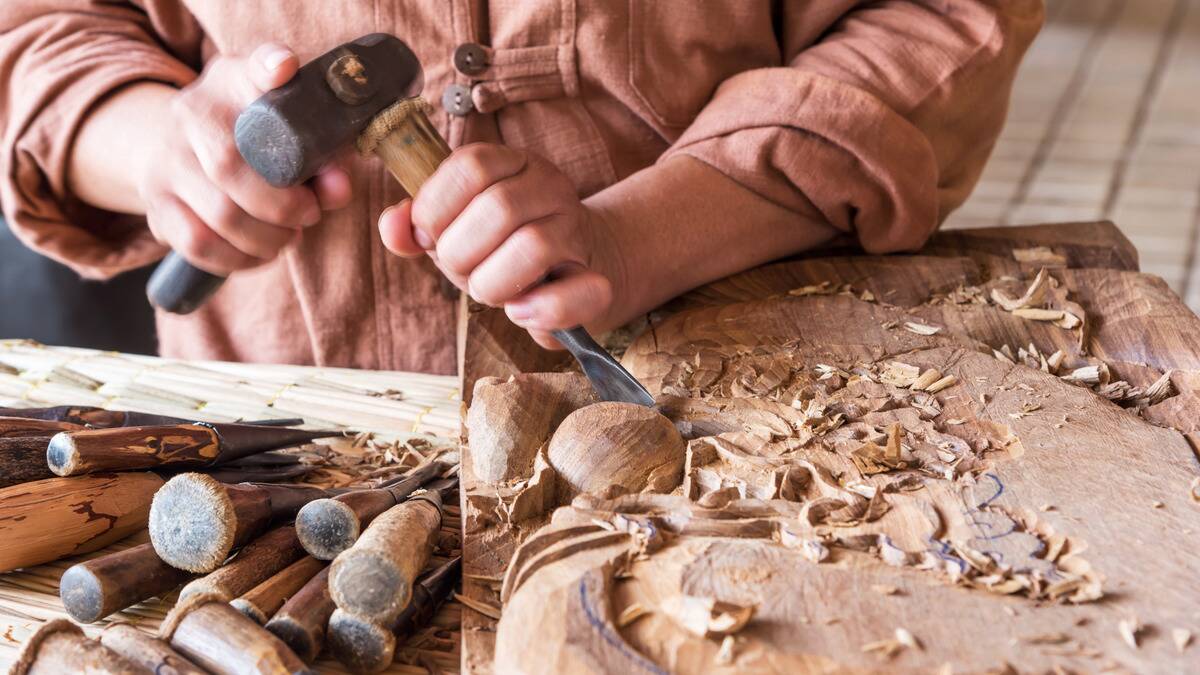 A close shot of someone whittling away at a block of wood.