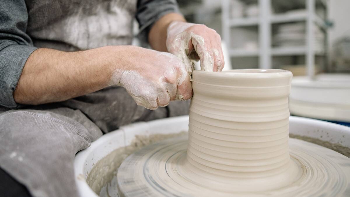 A close shot of a potter building a planter pot on a pottery wheel.