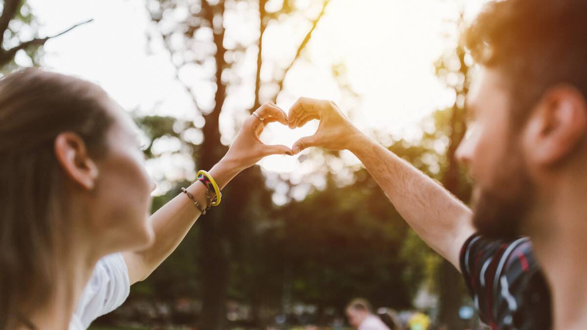 A couple making a heart with their hands, holding it up in the air.