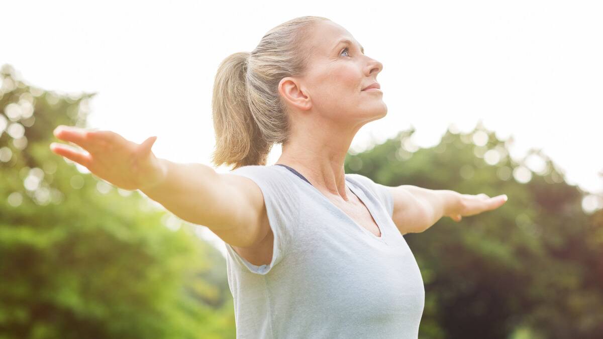 A woman doing yoga outside, arms stretched out