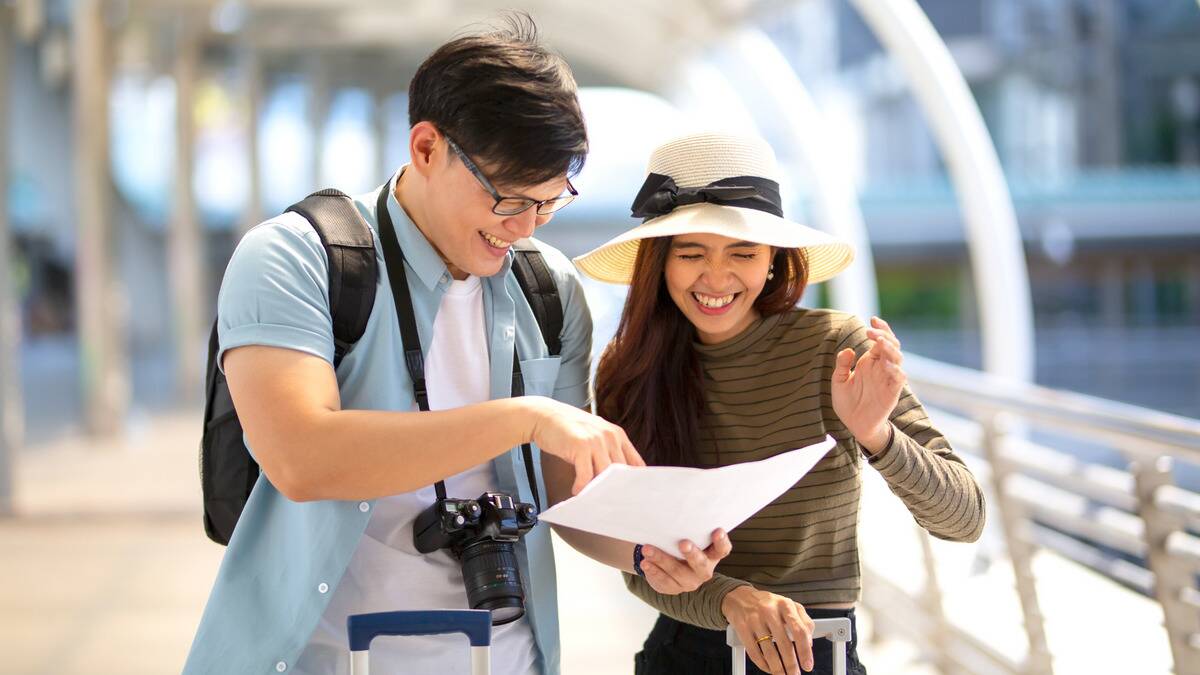 A couple on vacation, both smiling as they work out a map.