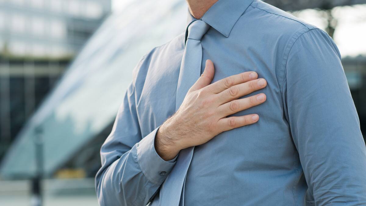A man in a dress shirt and tie placing his hand over his heart.