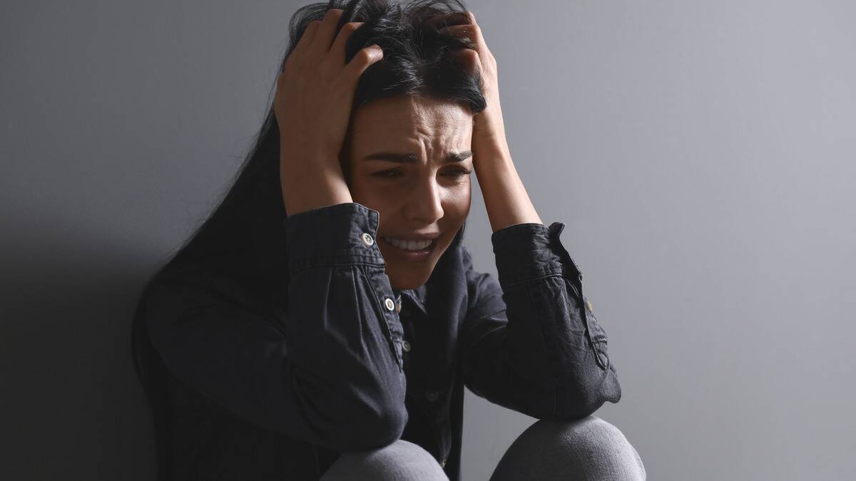 A woman clutching her head, looking afraid and panicked.