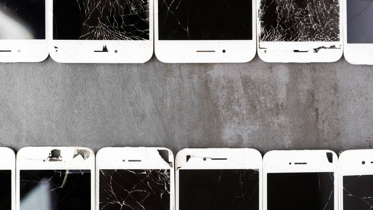 Two rows of white phones with cracked screens lining the top and bottom of the photo.