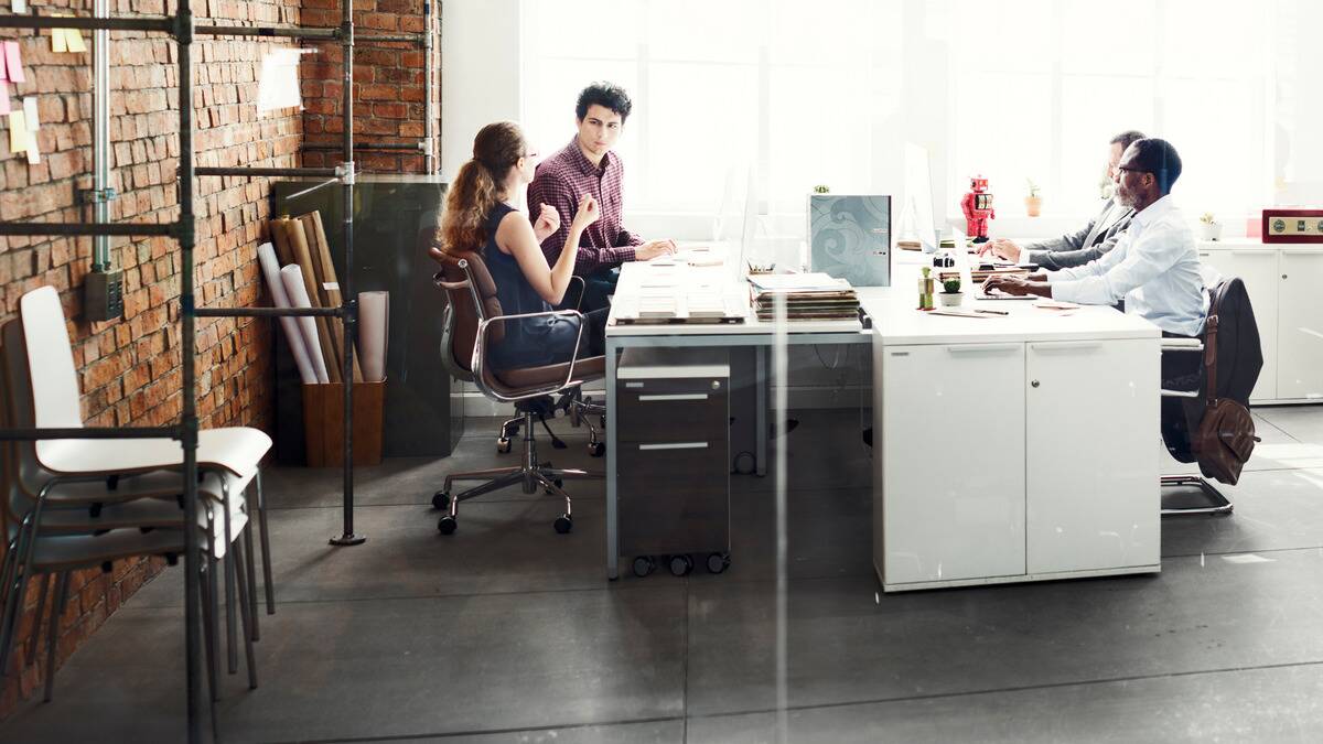 Four coworkers sat around a shared desk space, chatting.