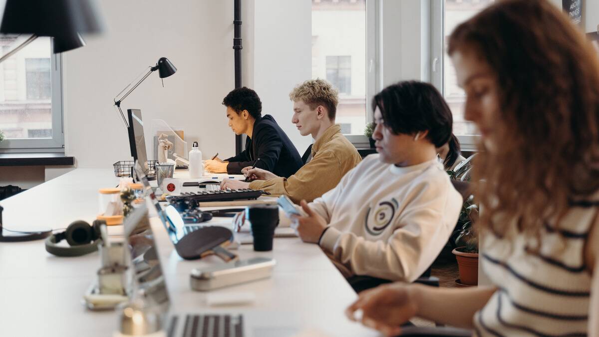 A side angle of a row of employees working at a large table.