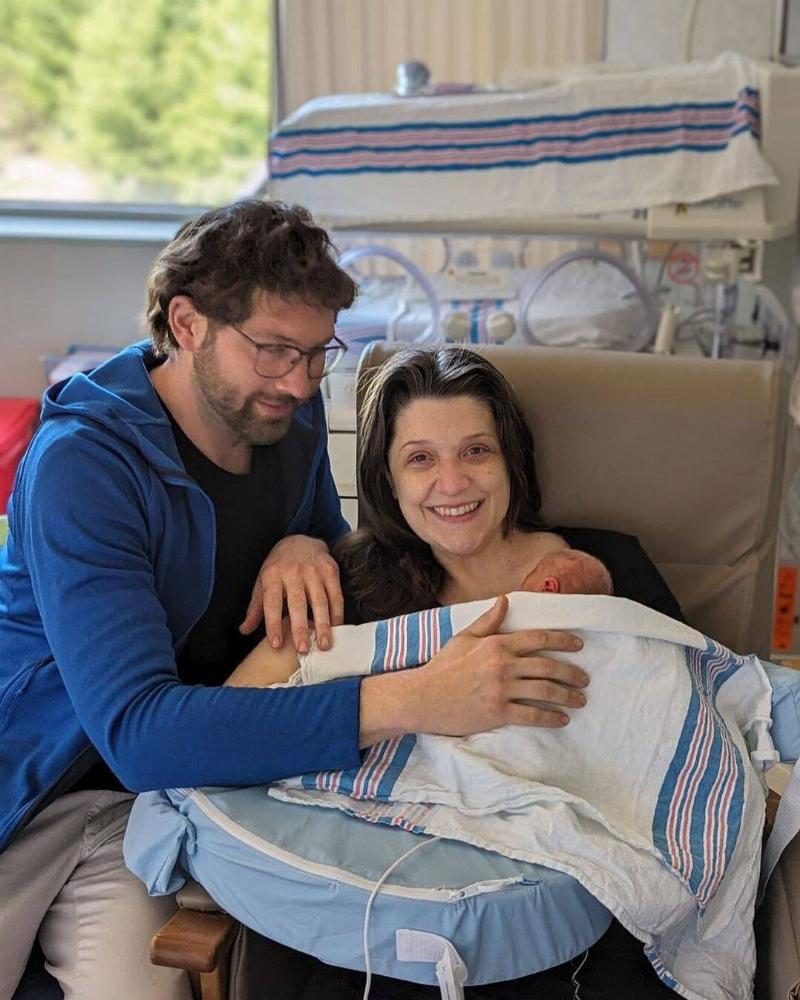 Nora and Michael with their baby, sitting in the hospital.