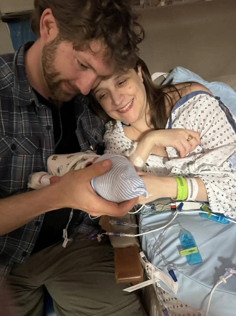 Nora and Michael holding their newborn baby in the hospital.