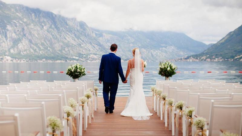 A couple on their wedding day holding hands as they walk down the aisle of their lakeside wedding.