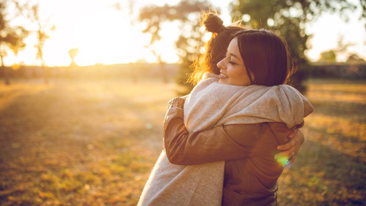 Two friends hugging in the sunshine.