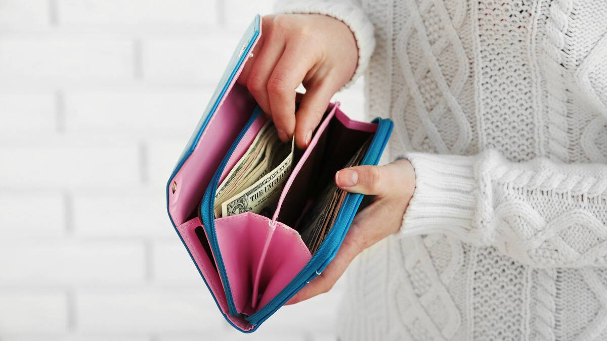 A pair of hands counting bills out of a colorful wallet.