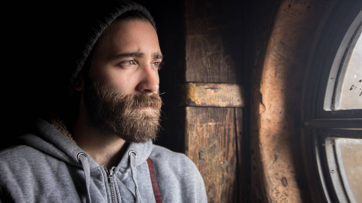 A man looking forlornly out a window.