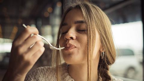 A woman eating something delicious, fork to her mouth.