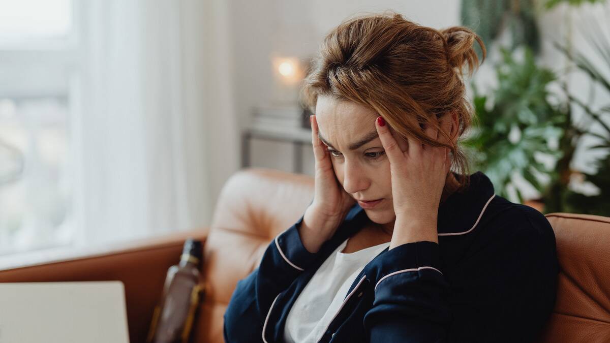 A woman holding her head with her hands, looking stressed out.