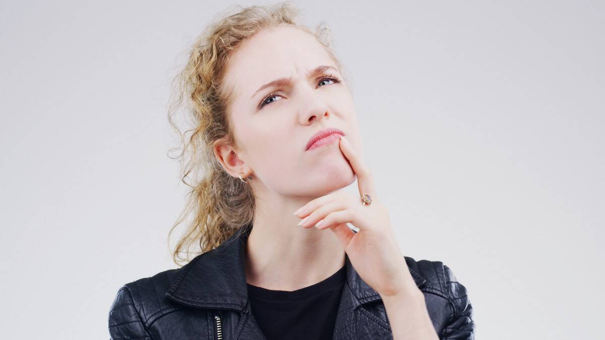 A woman thinking hard about something, hand on her chin.