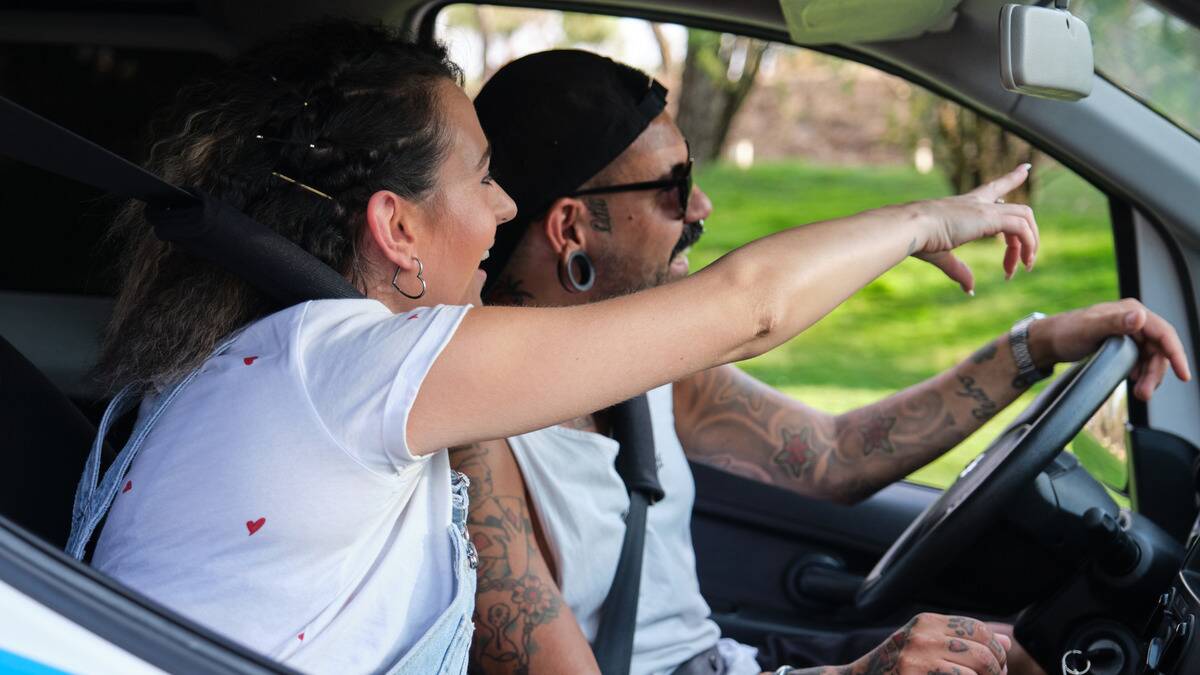 A couple driving around, the woman in the passenger seat excitedly pointing at something out the front window.