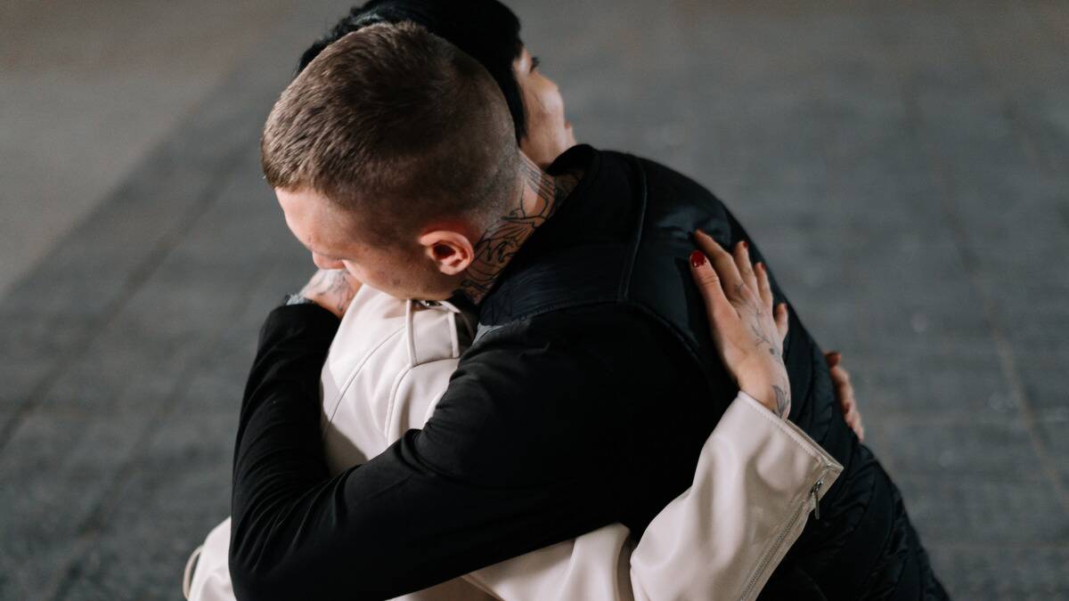 Two friends hugging tightly as they stand outside.