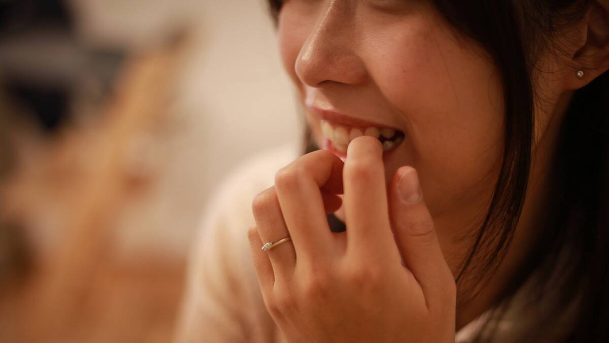 A close shot of a woman biting her nails anxiously.