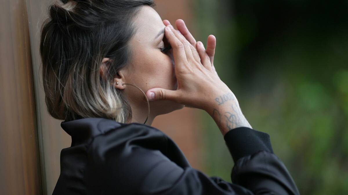 A woman with her hands to her face, looking stressed out.