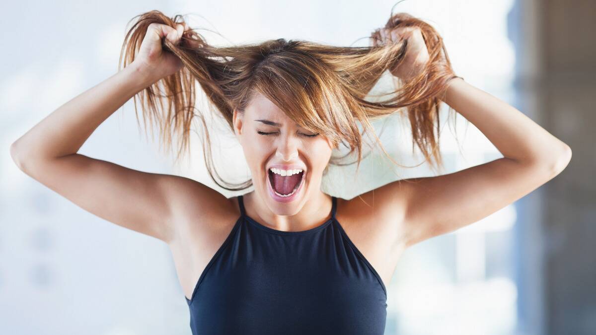 A woman screaming while pulling at her hair.