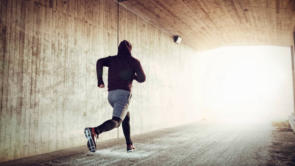 A man running down a hallway, a bright light at the end of it.