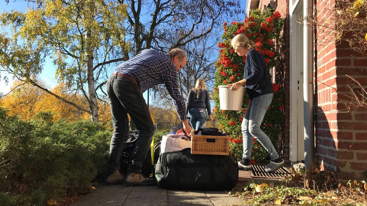 Parents helping their daughter unload her stuff into the walkway of their home, preparing for her to move out.