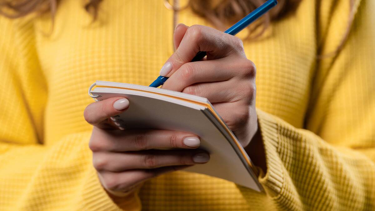 A close shot of a woman writing in a notepad.