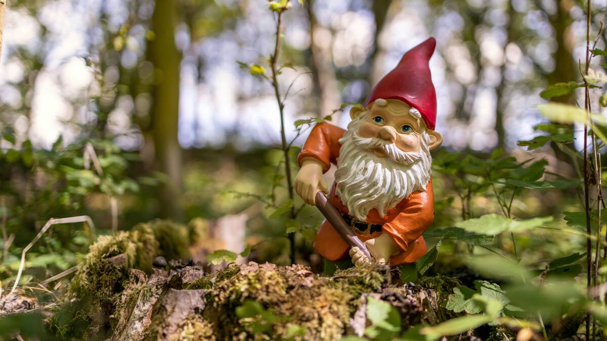 A gnome placed on a tree stump, posed as if he's digging into the wood.