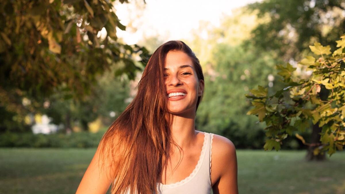 A woman sitting outside at the camera, as she sits in the sun.