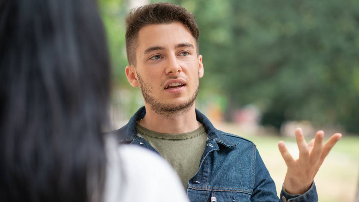 An over-the-shoulder shot of a man talking to a friend outside.