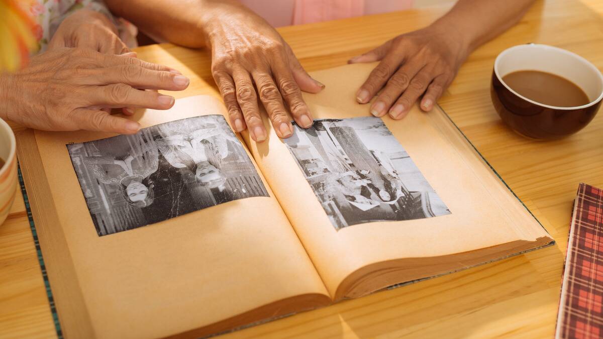 Two sets of hands looking at old photos in a photo album.