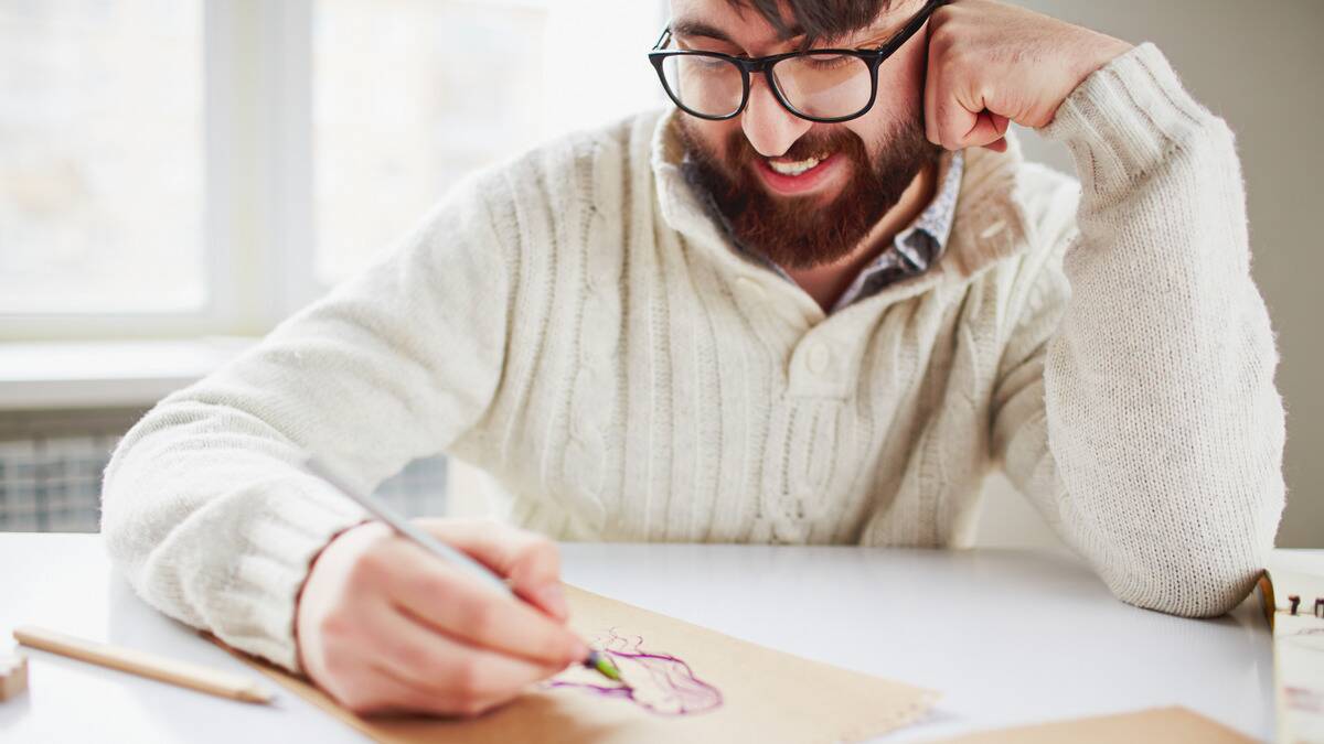 A man smiling as he draws.