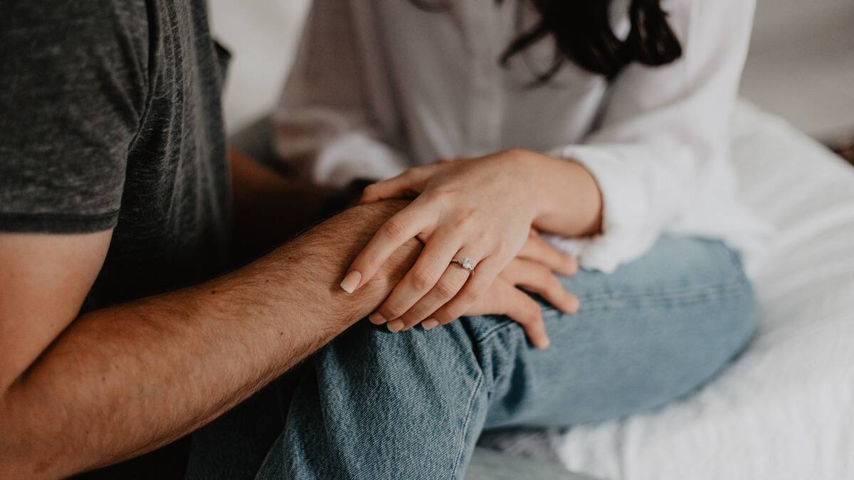 A close shot of a couple holding hands as they cuddle.