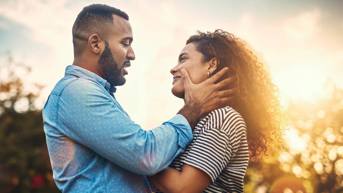 A couple facing each other, the man's hands holding the sides of the woman's face.