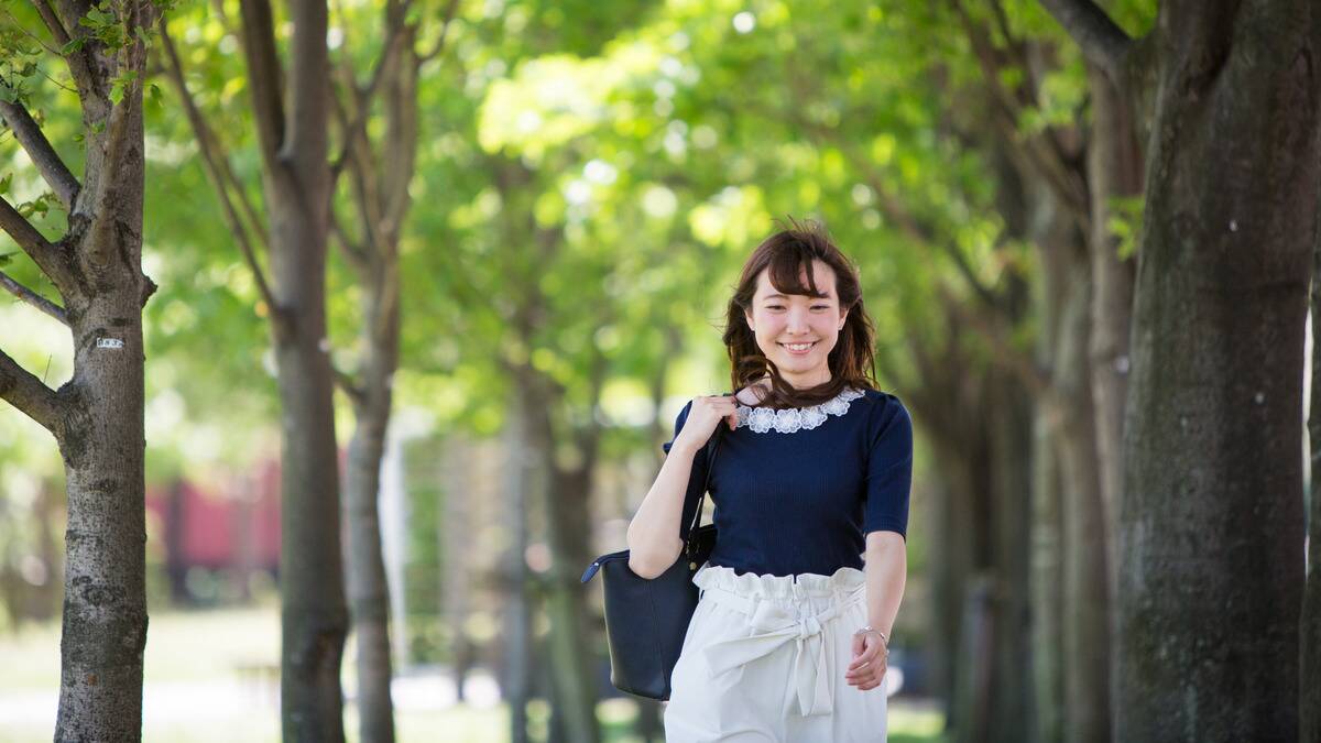 A woman smiling as she walks down the street in summer.