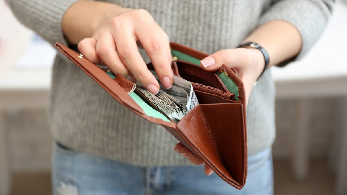 A close shot of a woman sorting through the stack of bills in her wallet.