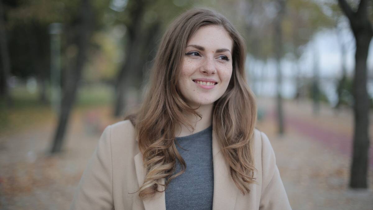 A woman smiling as she walks in the autumn outside.